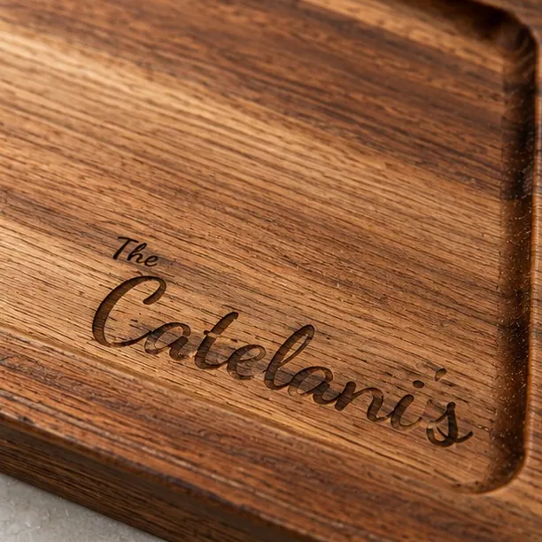 An acacia board in the script layout, engraved with a family name